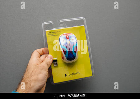 Paris, France - Oct 21, 2017: Man hand holding Logitech m317c wireless mouse isolated on gray background - new cardboard box Stock Photo