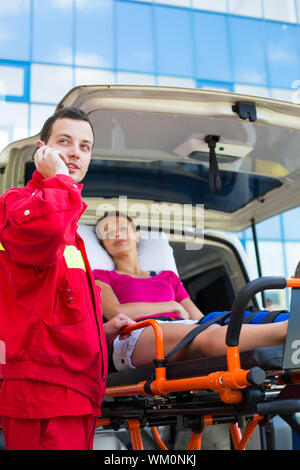 Paramedic taking care of a female patient - calling a hospital