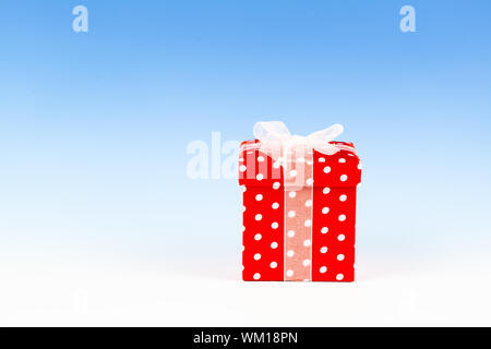red gift box, polka dots with bow on blue background Stock Photo
