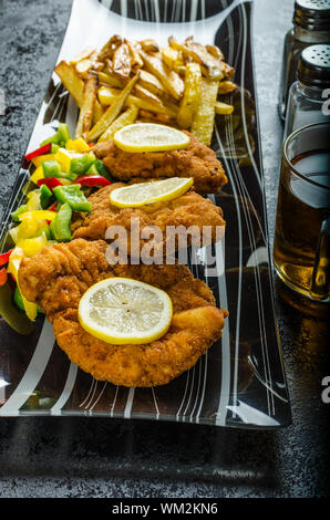 Schnitzel with french fries, homemade, platter, czech beer, vegetable, lemons Stock Photo