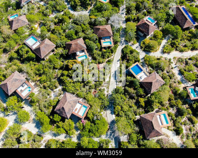 Aerial view of luxury villa with swimming pool in tropical forest. Private tropical villa with swimming pool among tropical garden with palm trees