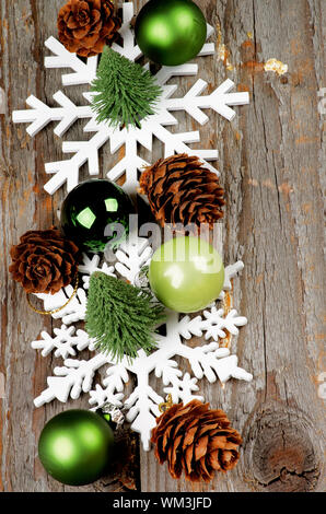 Arrangement of Little Christmas Trees, Green Baubles, Decorative Fir Cones and Snowflake Shapes In a Row on Rustic Wooden background Stock Photo