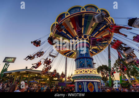 Vancouver, British Columbia, Canada - August 25, 2019: Kids are having fun on the swing carousel ride in PNE during a vibrant summer sunset. Stock Photo