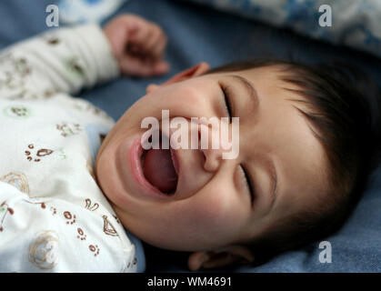 Happy six month old baby on bed Stock Photo