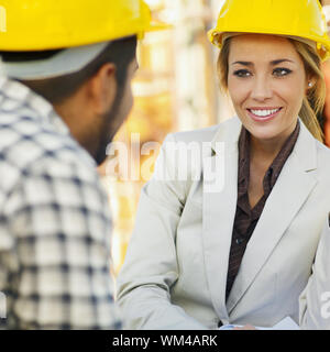 latin american construction worker and female architect talking. Stock Photo