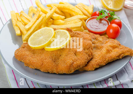 Schnitzel with french fries and a spicy dip, fresh from red orange Stock Photo