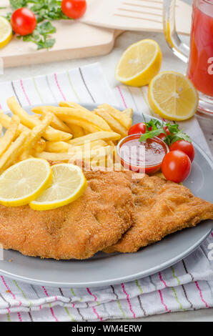 Schnitzel with french fries and a spicy dip, fresh from red orange Stock Photo