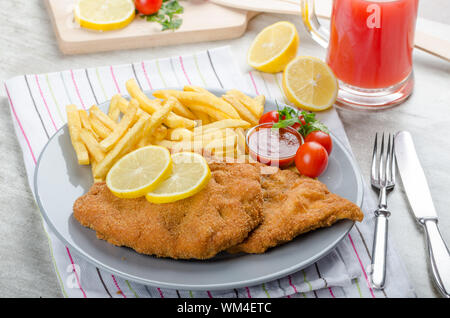 Schnitzel with french fries and a spicy dip, fresh from red orange Stock Photo