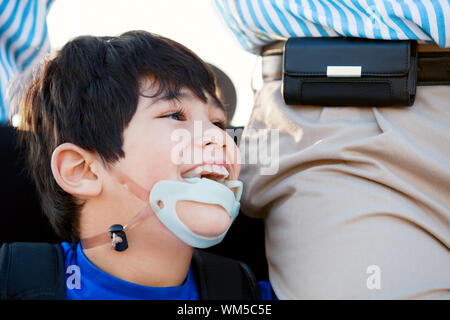 Disabled little boy in wheelchair next to father Stock Photo