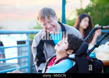 Father talking with disabled son in wheelchair Stock Photo