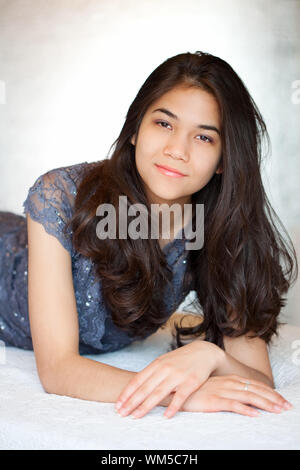 Beautiful biracial teen girl on formal dress lying down, relaxing Stock Photo