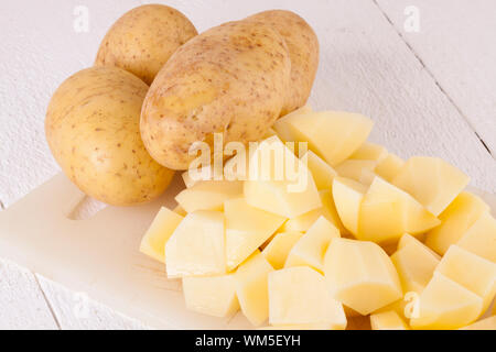 Whole Potatoes and Chopped Pieces on Cutting Board Stock Photo