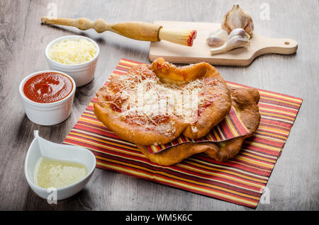 Traditional carnival fast food specialty, fried yeast dough with cheese, ketchup and garlic Stock Photo