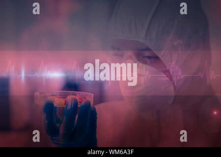 Scientist in protective suit analyzing pills against ecg line in red and black Stock Photo