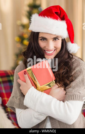 Festive brunette pressing gift at christmas at home in the living room Stock Photo