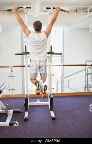 Fit man doing pull ups in fitness studio at the gym Stock Photo