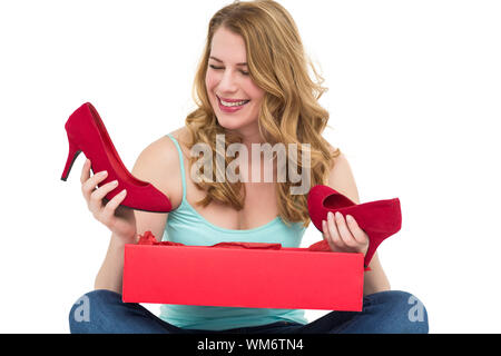 Blonde woman discovering shoes in a gift box on white background Stock Photo