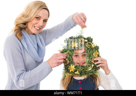 Festive mother and daughter holding christmas wreath on white background Stock Photo