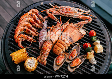 Lobster, rock lobster and mix seafood barbecue cokking on grill - seafood dinner party concept Stock Photo