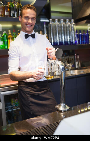 Handsome barkeeper pulling a pint of beer in a bar Stock Photo