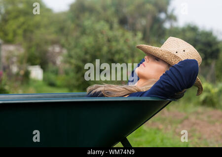Pretty blonde napping in wheelbarrow at home in the garden Stock Photo