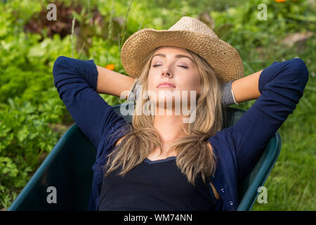 Pretty blonde napping in wheelbarrow at home in the garden Stock Photo