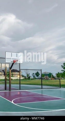 Outdoor Basketball Court with Homes and Mountain Against Overcast