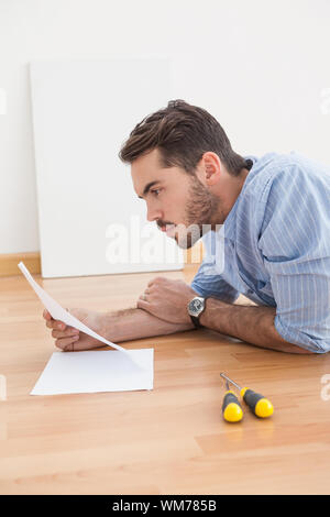 Casual man reading instruction manual for power tool at home in the living room Stock Photo
