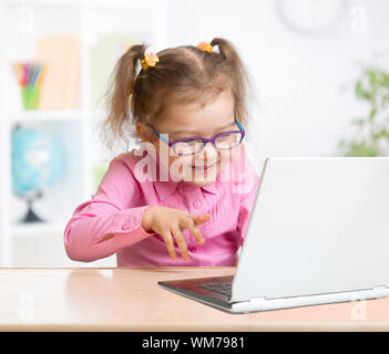 Happy kid in spectacles using notebook with great interest in school Stock Photo