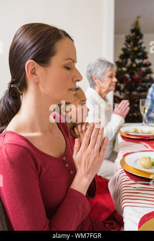 Extended family praying before christmas dinner at home in the living room Stock Photo