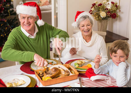 Grandfather in santa hat carving roast turkey at christmas at home in the living room Stock Photo