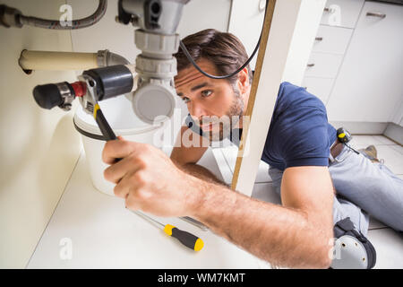 Plumber fixing under the sink in the kitchen Stock Photo