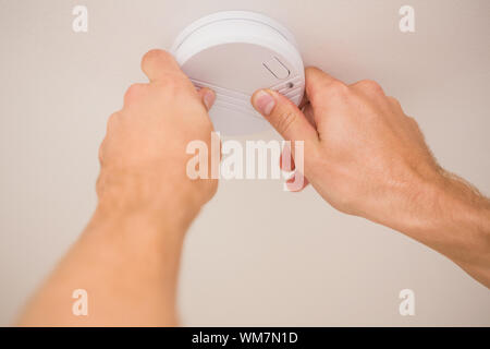 Handyman installing a smoke detector on the ceiling Stock Photo