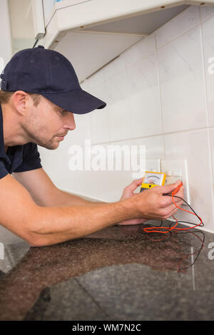 Electrician metering voltage with digital multimeter in the kitchen Stock Photo