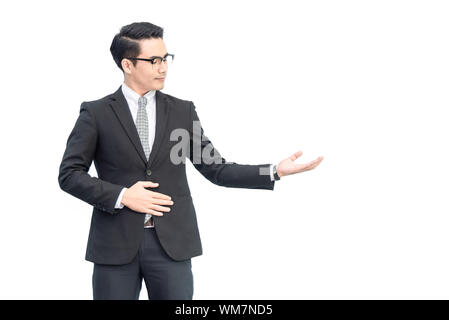 Happy young confident asian businessman with eyes glasses in formal black suit showing hand blank area for advertisement, sign, text, slogan .with cop Stock Photo