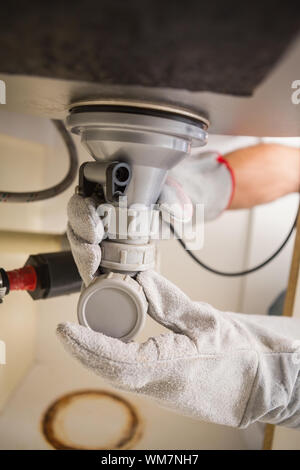 Plumber fixing under the sink in the kitchen Stock Photo