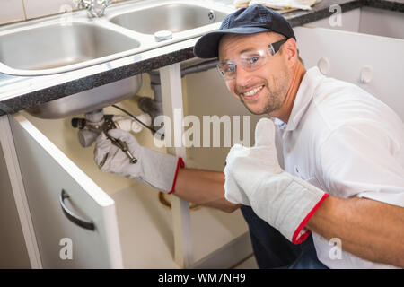 Plumber fixing under the sink in the kitchen Stock Photo