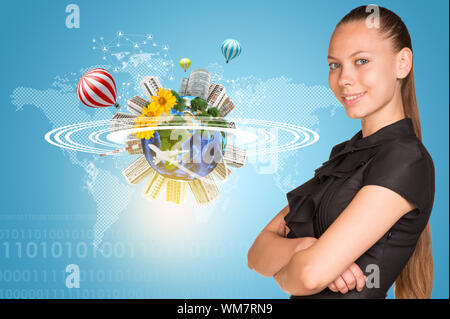 Beautiful businesswoman smiling and looking at camera. Beside is miniature Earth with trees, flowers, industrial and residential buildings, air balloo Stock Photo