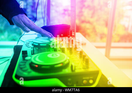 Hand of Technician using Sound system mixing audio equipment board on stage with soft light.DJ mixing sound in party at pub and bars with colorful eff Stock Photo