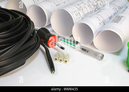 Drawing rolls, triple cable, screwdrivers, test pen, terminal block on white surface Stock Photo