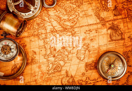 Vintage magnifying glass, compass, telescope and a pocket watch lying on an old map in 1565. Stock Photo