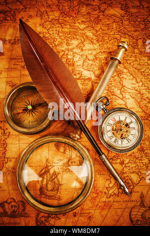 Vintage compass, magnifying glass, pocket watch, quill pen on an old ancient map in 1565. Vintage still life. Stock Photo