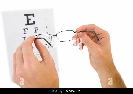 Glasses held up to read eye test on white background Stock Photo