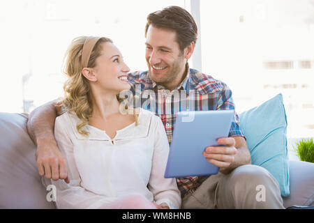 Couple using tablet pc while looking at each other in bright living room Stock Photo