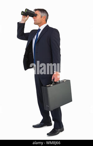 Businessman in suit looking through binoculars on white background Stock Photo