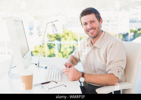 Smiling businessman looking at document at his desk in his office Stock Photo