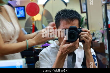 I am taking image of myself in the mirror with DSLR camera during having a hair cut Stock Photo