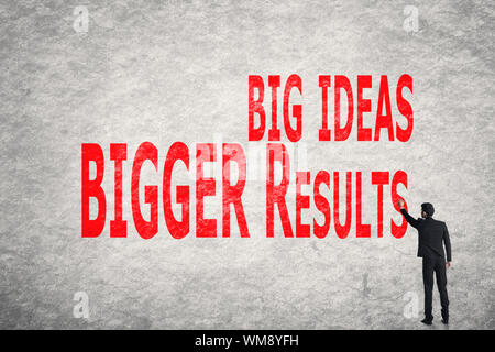 Asian business man write words on wall, Big Ideas Bigger Results Stock Photo