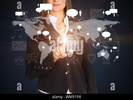 Businesswoman touches future style sensor screen on which there is map of the world with connection points and large icons. On dark background Stock Photo
