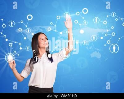 Businesswoman touches virtual network with people icons. Light blue background with world map and faint icons Stock Photo